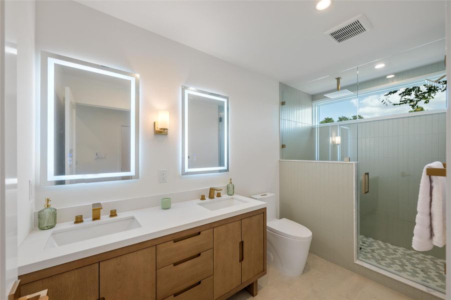 A well-appointed primary bathroom showcases dual vanities, contemporary fixtures, and a spacious glass-enclosed shower. A well-appointed primary bathroom showcases dual vanities, contemporary fixtures, and a spacious glass-enclosed shower.