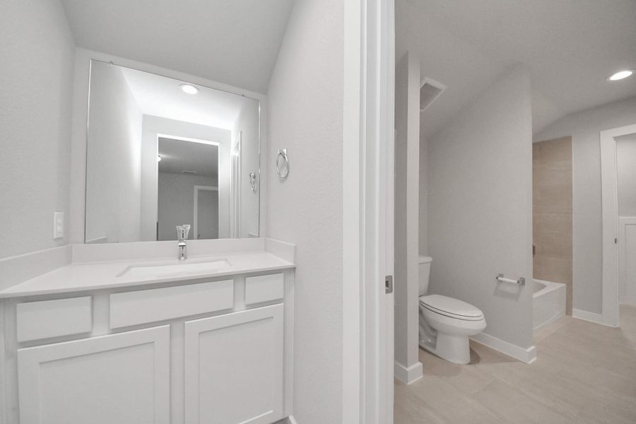 Experience convenience in the secondary bathroom, designed for Jack and Jill arrangements, now with a separate vanity area. This well-appointed space showcases stylish tile flooring, a bath/shower combo with an elegant tile surround, and light-stained wood cabinets. The beautiful light countertop adds a touch of sophistication, combining functionality and aesthetics seamlessly. Experience convenience in the secondary bathroom, designed for Jack and Jill arrangements, now with a separate vanity area. This well-appointed space showcases stylish tile flooring, a bath/shower combo with an elegant tile surround, and light-stained wood cabinets. The beautiful light countertop adds a touch of sophistication, combining functionality and aesthetics seamlessly.