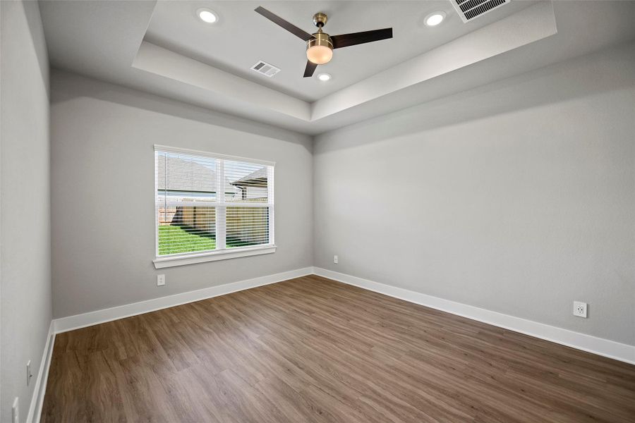 Large windows fill the room with soft light, offering serene views of the backyard.