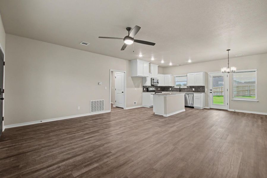 An open-concept living area seamlessly connects to the modern kitchen with durable plank flooring.