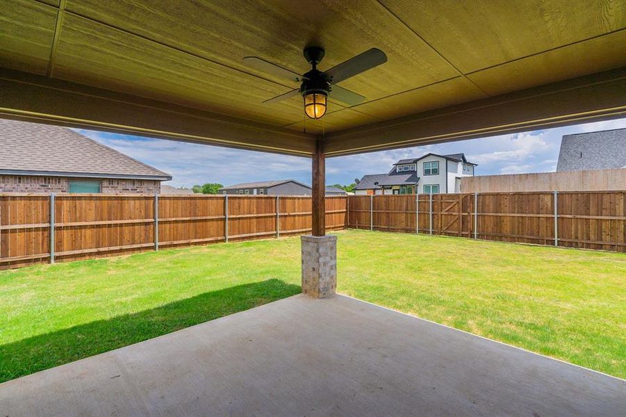 Covered patio, complete with inlaid finished ceiling; farmhouse lighted ceiling fan, overlooking expansive yard with stained privacy fence - this is lovely!