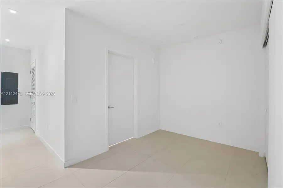 Interior space featuring neutral large-format floor tiles, recessed ceiling lighting, and solid-core interior doors