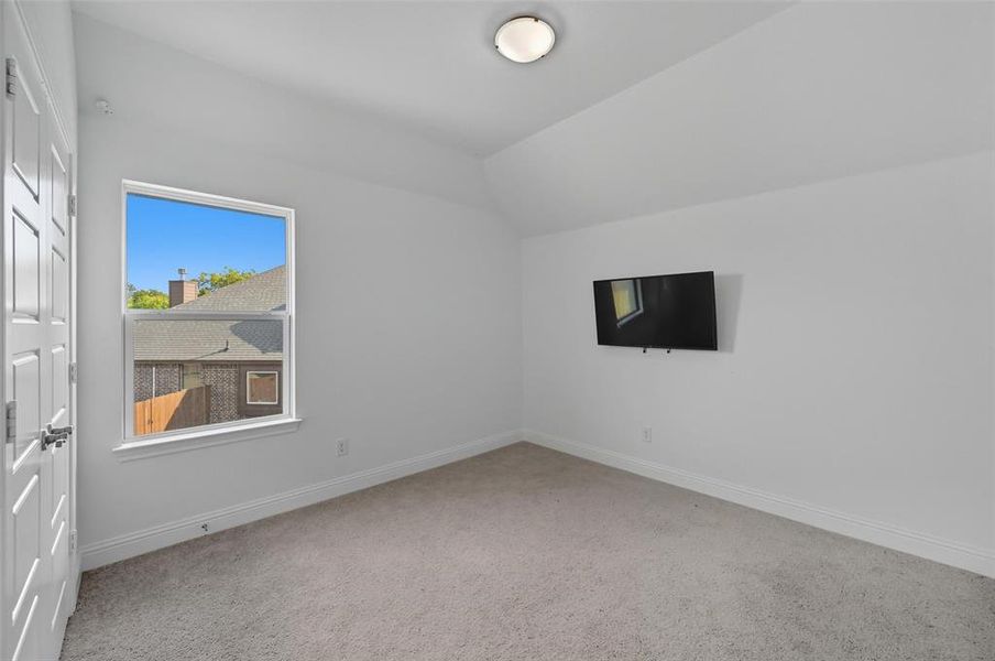 Empty room featuring light carpet and lofted ceiling