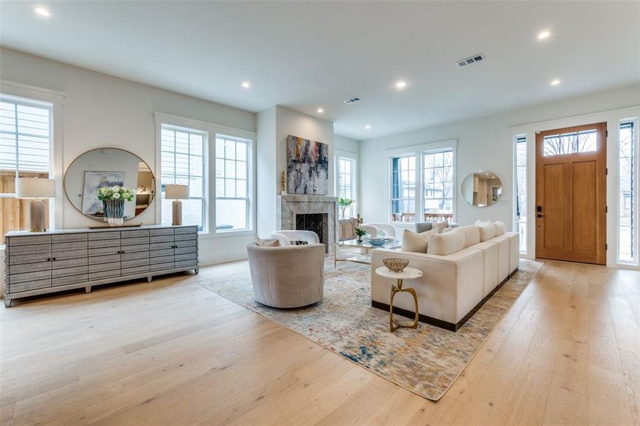 Living room featuring a wealth of natural light, a premium fireplace, and light wood-type flooring