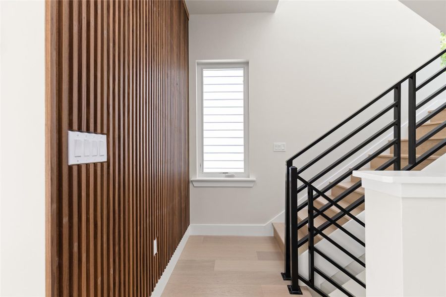 A contemporary wood-slat feature wall pairs with a modern staircase and light hardwood flooring.