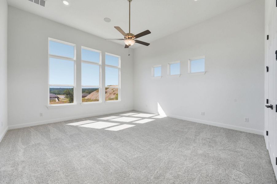 Spare room featuring plenty of natural light, light carpet, a ceiling fan, and recessed lighting
