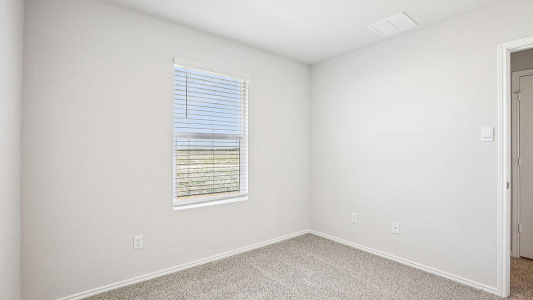 Bright room featuring neutral-toned walls, plush carpet flooring, a window with horizontal blinds, and a white interior door
