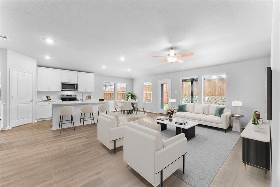 Living room featuring recessed lighting, ceiling fan, and light wood-style flooring Living room featuring recessed lighting, ceiling fan, and light wood-style flooring
