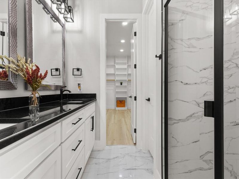 Spacious bathroom featuring a dual vanity with black countertops, white cabinetry, and matte black hardware Spacious bathroom featuring a dual vanity with black countertops, white cabinetry, and matte black hardware