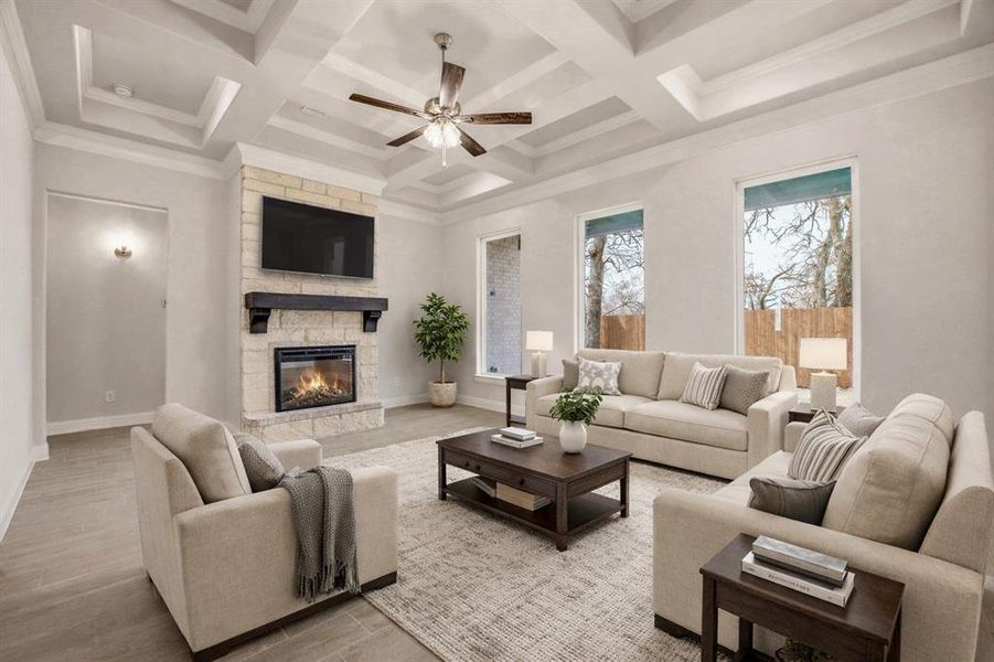 Living room with ceiling fan, a fireplace, wood finished floors, coffered ceiling, and crown molding