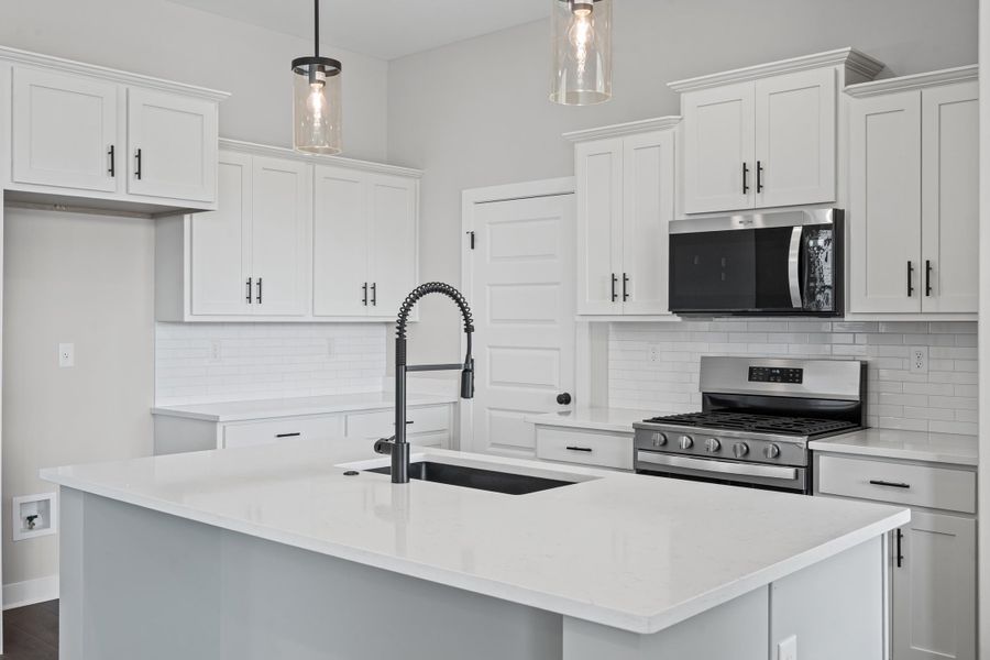 Kitchen featuring decorative backsplash, appliances with stainless steel finishes, an island with sink, and light stone counters Kitchen featuring decorative backsplash, appliances with stainless steel finishes, an island with sink, and light stone counters