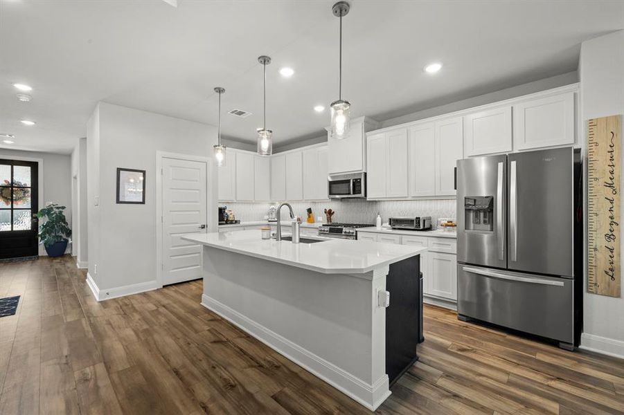 Kitchen with appliances with stainless steel finishes, white cabinets, a center island with sink, backsplash, and recessed lighting Kitchen with appliances with stainless steel finishes, white cabinets, a center island with sink, backsplash, and recessed lighting