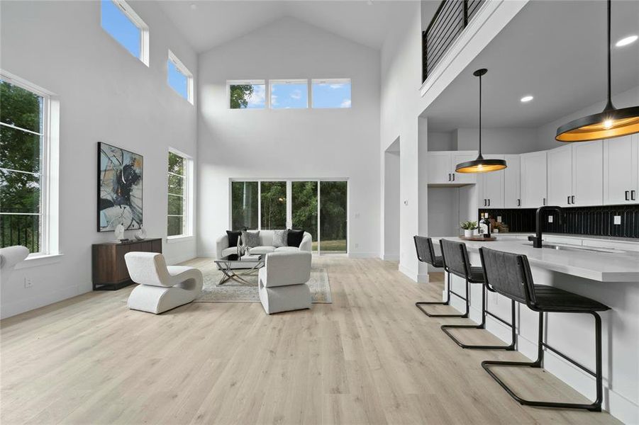 Living room with a high ceiling, light wood finished floors, and plenty of natural light Living room with a high ceiling, light wood finished floors, and plenty of natural light
