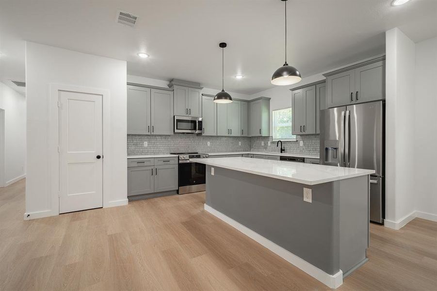 Kitchen featuring stainless steel appliances, gray cabinets, light wood finished floors, tasteful backsplash, and recessed lighting Kitchen featuring stainless steel appliances, gray cabinets, light wood finished floors, tasteful backsplash, and recessed lighting