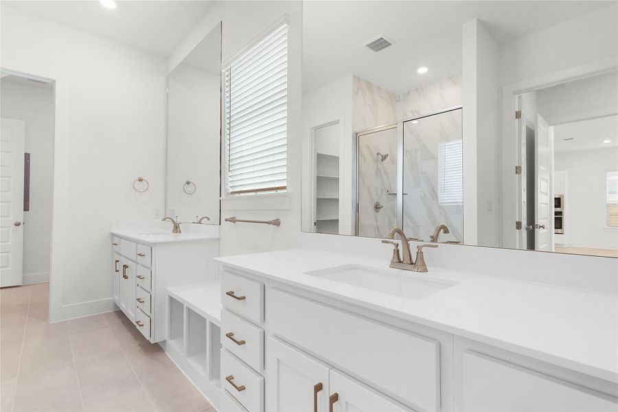 Full bathroom featuring a marble finish shower, two vanities, light tile patterned flooring, and recessed lighting