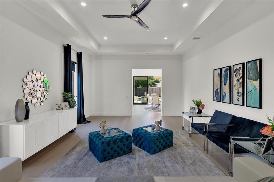 Living room featuring a tray ceiling and ceiling fan