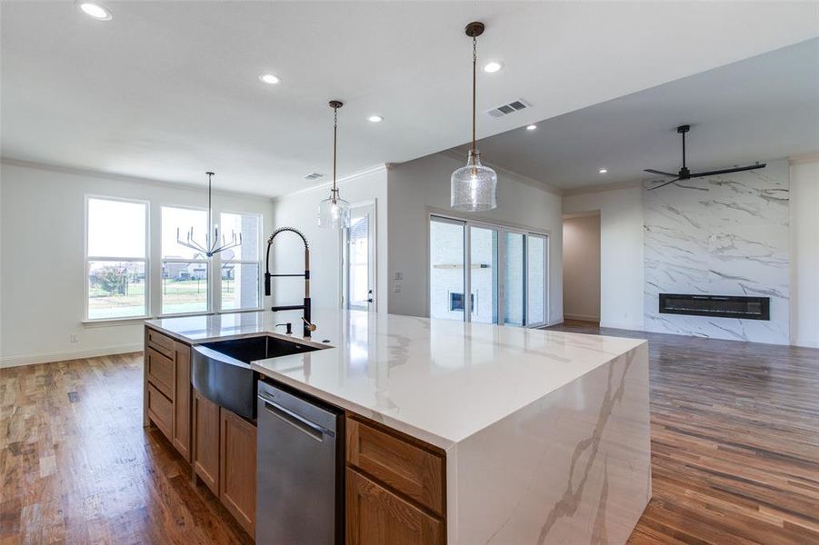 Kitchen featuring dishwasher, a spacious island, a fireplace, and dark hardwood / wood-style flooring