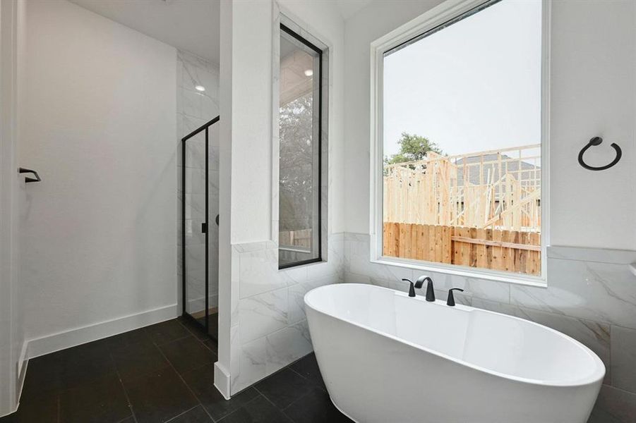 Full bathroom with a soaking tub, tile walls, a stall shower, a wainscoted wall, and dark tile patterned floors Full bathroom with a soaking tub, tile walls, a stall shower, a wainscoted wall, and dark tile patterned floors