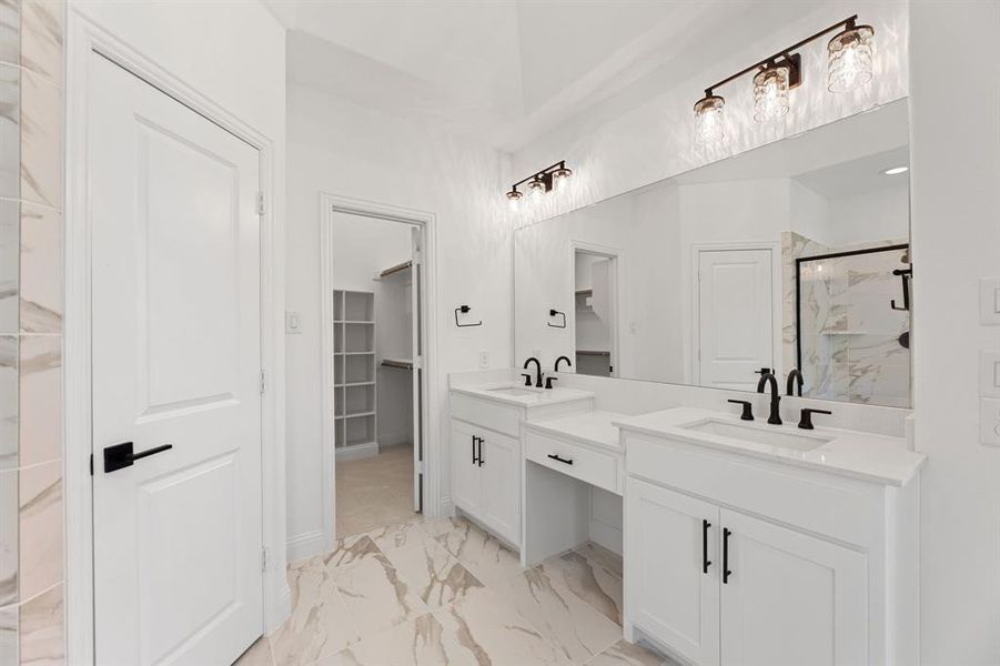Full bath with a walk in closet, a marble finish shower, double vanity, and light marble finish floors Full bath with a walk in closet, a marble finish shower, double vanity, and light marble finish floors