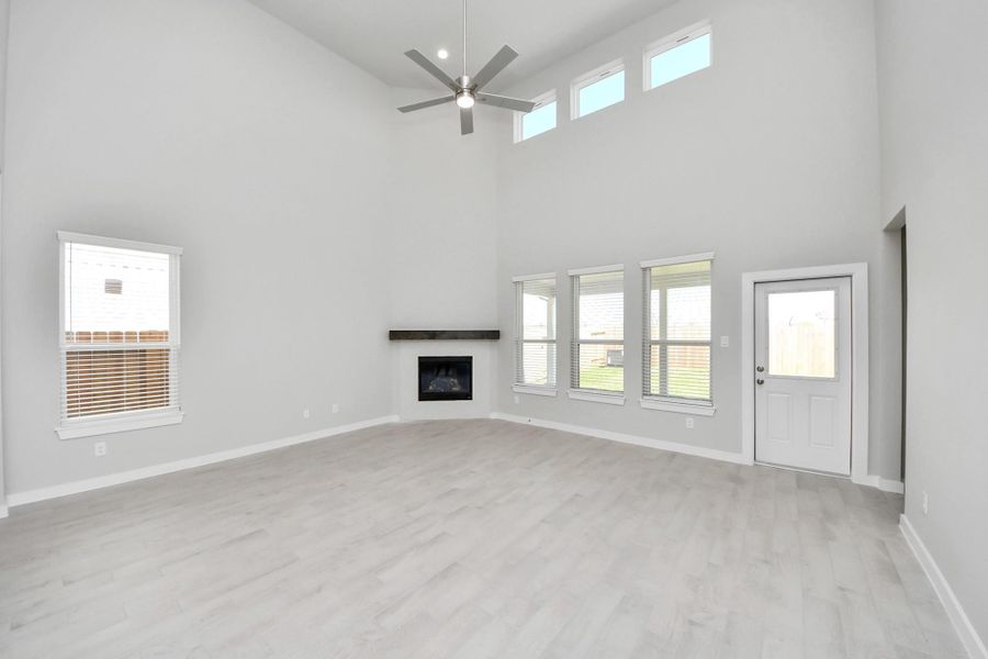 Welcome family and guests to your charming living room! With its high ceilings, recessed lighting, ceiling fan, custom paint, beautiful flooring, and large windows that let in abundant natural light, this room is perfect for gatherings. Sample photo of completed home with similar floor plan. Actual colors and selections may vary.