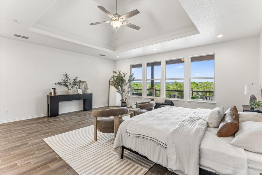 Sun-filled primary bedroom with a gorgeous view and tray ceilings creates a serene retreat.