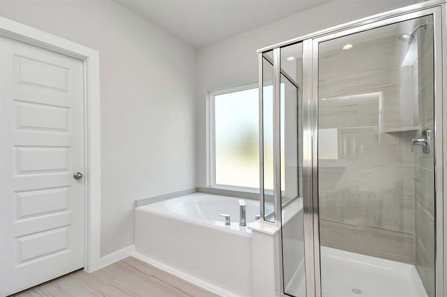 Experience luxury in this spa-like primary bathroom featuring a massive walk-in shower with tile surround. Sample photo of completed home with similar floor plan. As-built interior colors and selections may vary.