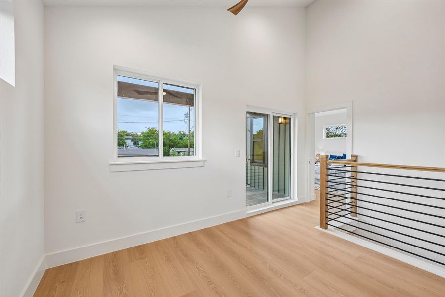 A well-lit upper-level space features sleek  flooring and a private balcony.