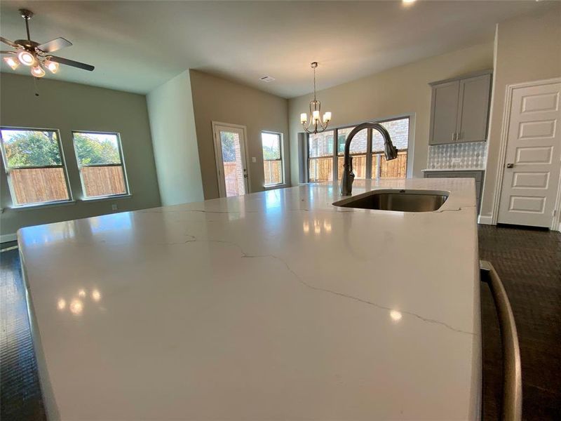 Enormous kitchen island with Monet quartz countertops and single basin stainless undermount sink.