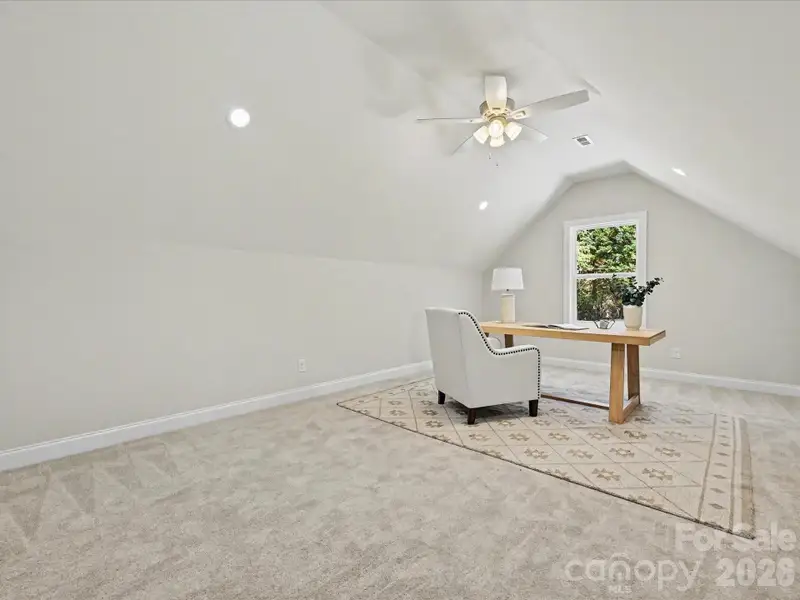 Versatile bonus room offers endless possibilities for a home office, media room, playroom, or additional guest space with cozy carpeting and vaulted ceilings.