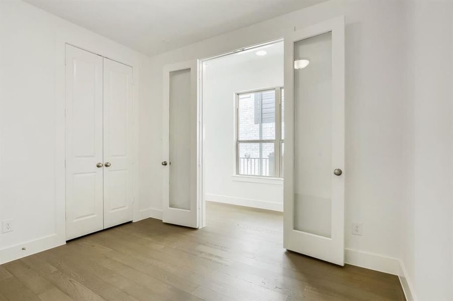 Room featuring wood-finish flooring, white walls, and bright baseboards
