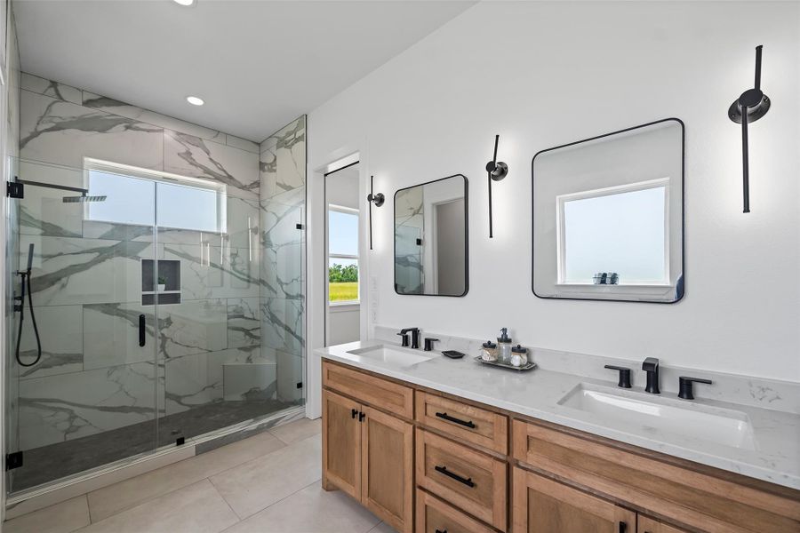 Luxurious primary bathroom featuring a sleek glass-enclosed shower, elegant dual vanities, and modern lighting for a spa-like retreat.