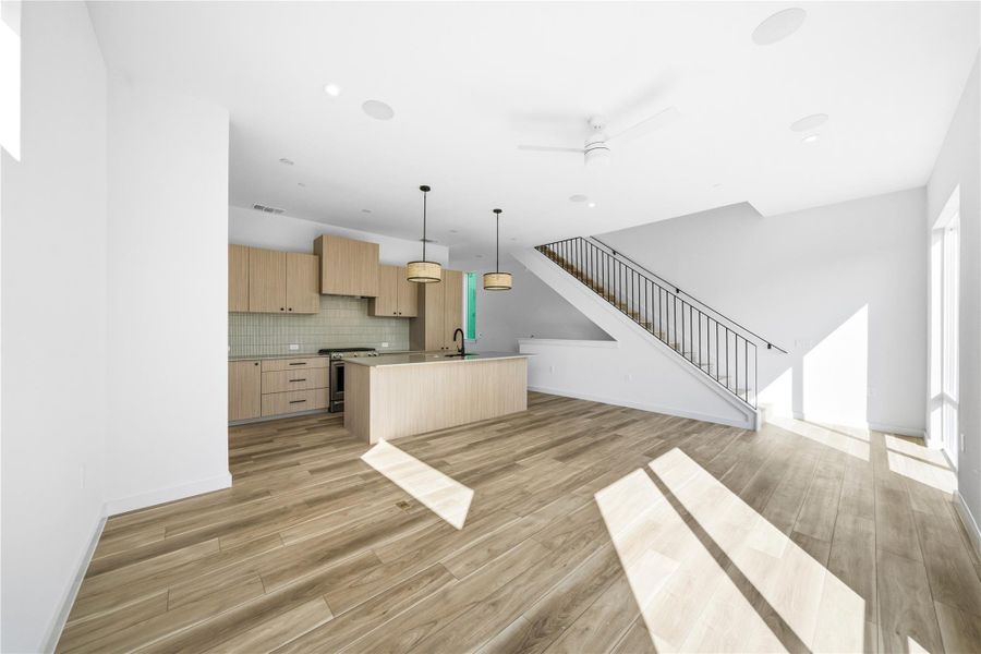 Kitchen featuring open floor plan, light brown cabinets, ceiling fan, pendant lighting, and an island with sink Kitchen featuring open floor plan, light brown cabinets, ceiling fan, pendant lighting, and an island with sink
