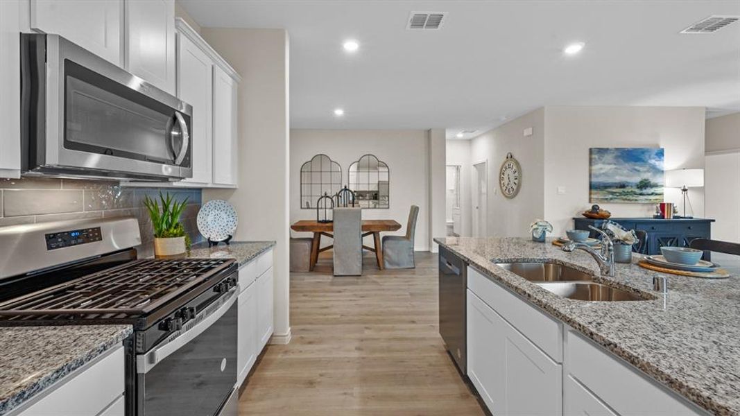 Kitchen with stainless steel appliances, white cabinetry, light wood finished floors, light stone countertops, and recessed lighting Kitchen with stainless steel appliances, white cabinetry, light wood finished floors, light stone countertops, and recessed lighting