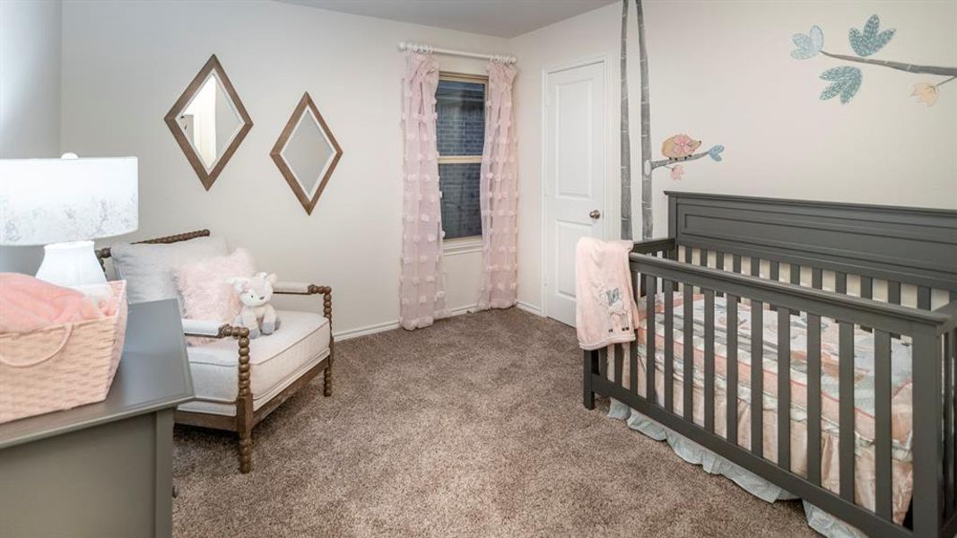 Carpeted bedroom with a nursery area and baseboards