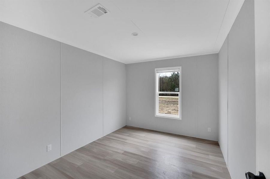 Empty room with a decorative wall and light wood-type flooring