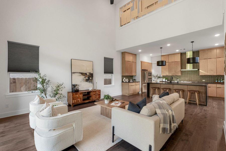 An open-concept living space with high ceilings flows seamlessly into a well-appointed kitchen.