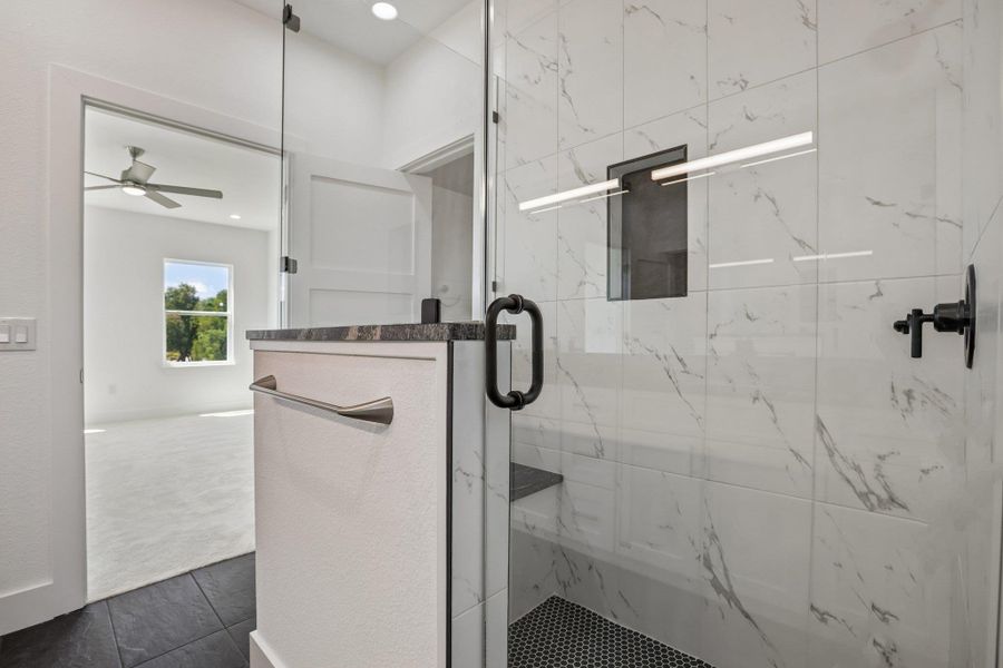 Elegantly veined wall tile and a frameless glass door highlight this modern walk-in shower.