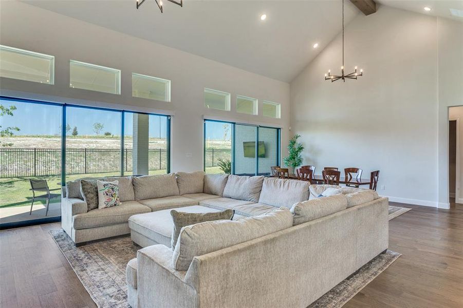 Living area featuring a chandelier, high vaulted ceiling, recessed lighting, dark wood-type flooring, and beam ceiling Living area featuring a chandelier, high vaulted ceiling, recessed lighting, dark wood-type flooring, and beam ceiling