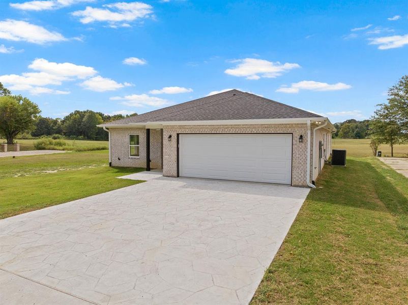 Ranch-style home featuring a front yard, concrete driveway, and brick siding