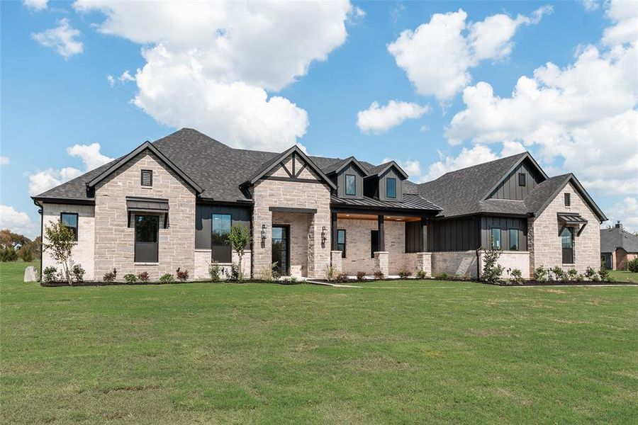 View of front of home featuring a standing seam roof, a front yard, a metal roof, and roof with shingles