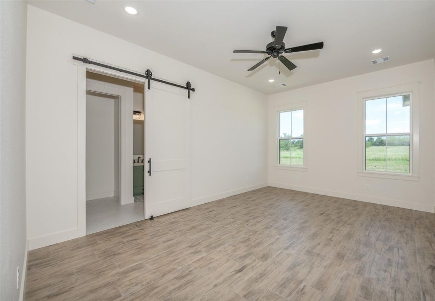 Unfurnished room featuring a barn door, light wood-style flooring, recessed lighting, and a ceiling fan