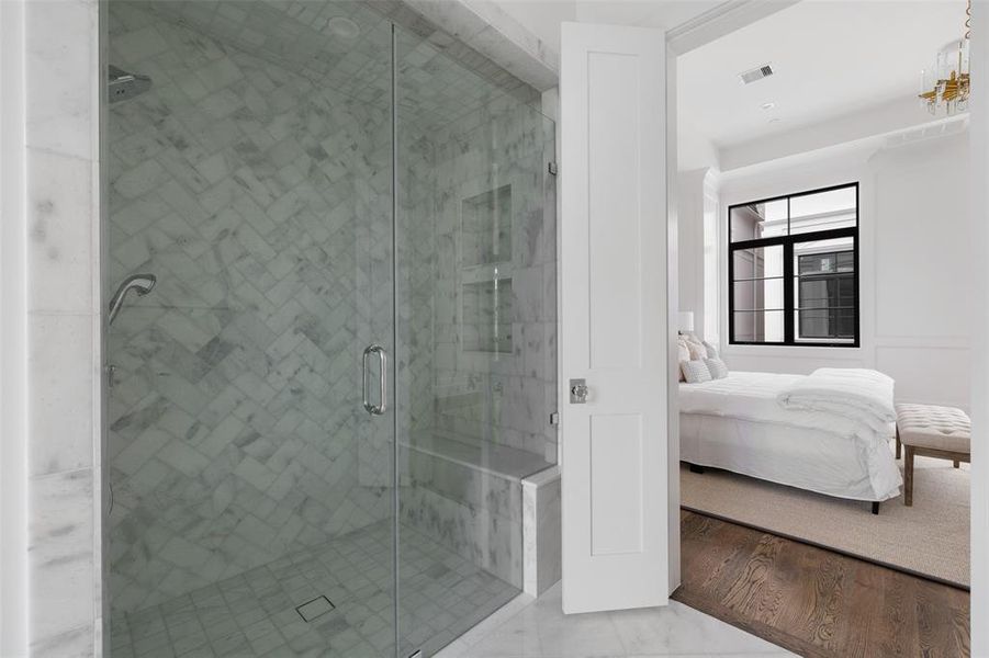 The spa-like retreat is complete with a frameless marble shower with over head rain shower, handheld sprayer, body spray jets and bench seating. Image from previously completed home in the community.