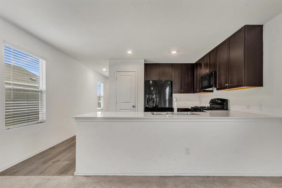 Dark cabinetry beautifully contrasts with light countertops and clean walls in this open kitchen layout. Dark cabinetry beautifully contrasts with light countertops and clean walls in this open kitchen layout.