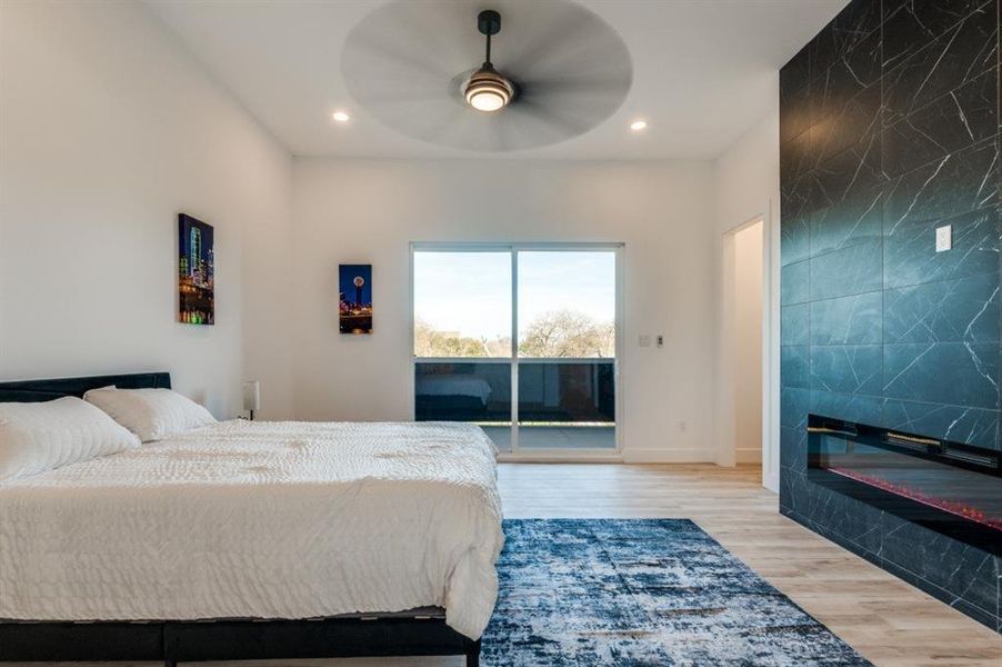 Elegant primary bedroom with breathtaking skyline vistas of Downtown Dallas, fireplace complemented by a secluded covered patio with a ceiling fan, creating a serene retreat. Elegant primary bedroom with breathtaking skyline vistas of Downtown Dallas, fireplace complemented by a secluded covered patio with a ceiling fan, creating a serene retreat.