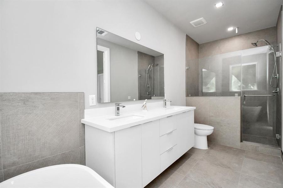 Modern bathroom featuring a sleek freestanding tub, floating vanity with a large mirror, and a separate toilet area. The space has neutral tones with a combination of tile and painted walls.