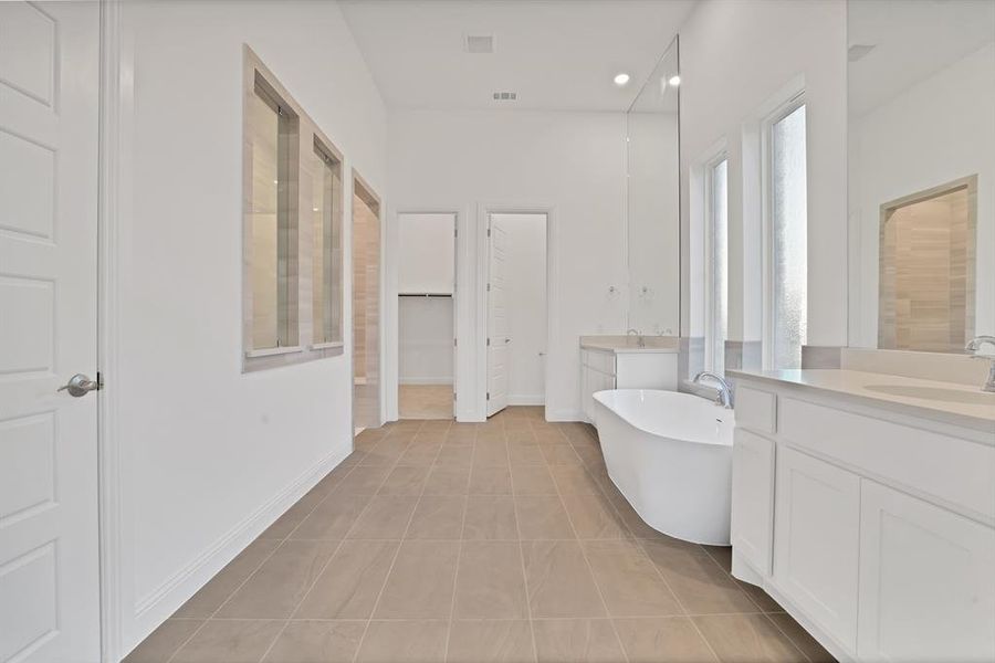 Bathroom featuring tile flooring, a bathtub, walk-in shower and two vanities