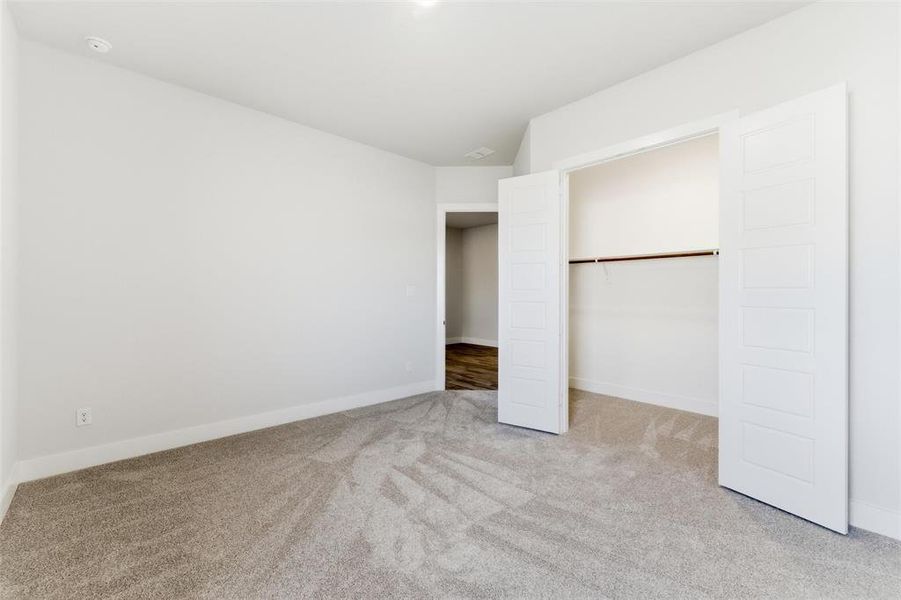 Unfurnished bedroom with light colored carpet and a closet
