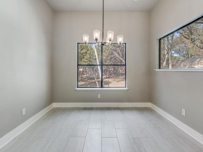 Spare room featuring suspended lighting, healthy amount of natural light, and wood tiled floors