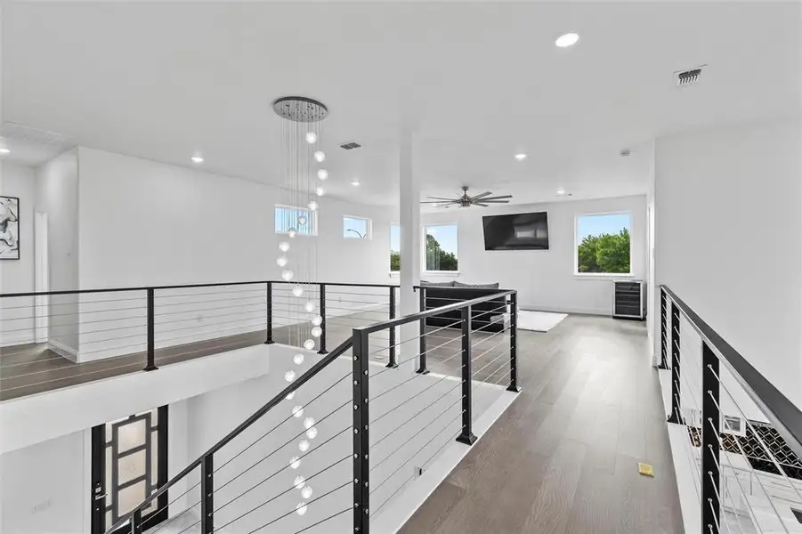 Upper-level landing featuring wood-finish flooring and contemporary cable railings