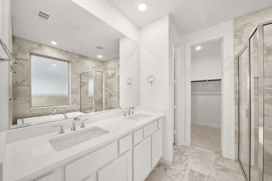 A bright primary bathroom featuring ample cabinets, a large mirror, and a window that fills the space with natural light. A bright primary bathroom featuring ample cabinets, a large mirror, and a window that fills the space with natural light.